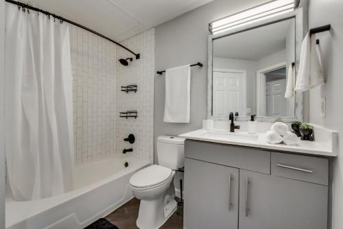 a white bathroom with a toilet and a sink at Loft Style 2BR Apt I Dallas City Center I Pool I Gym I Workspace I Pets in Dallas