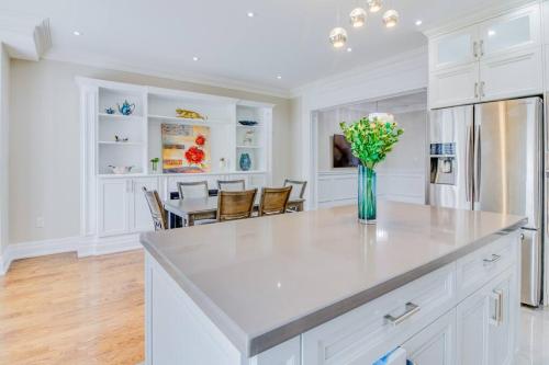 a kitchen with white cabinets and a vase of flowers at Luxury house, 25 minutes to Toronto Downtown in Toronto