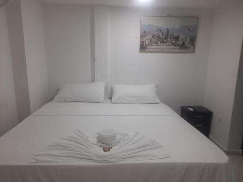 uma cama branca num quarto com uma fotografia na parede em HOTEL HOUSE CIA em Barrancabermeja