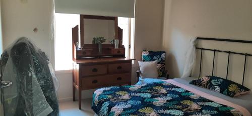 a bedroom with a bed and a dresser with a mirror at Frances's home in Gilles Plains