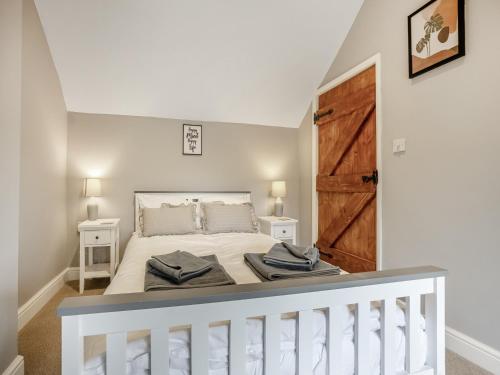 um quarto com uma cama branca e uma porta de madeira em Huntspill Cottage em Holbeach