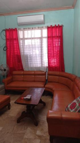 - un salon avec des canapés en cuir et des rideaux rouges dans l'établissement JVC Home (Beside Federico's Resto), à Ormoc