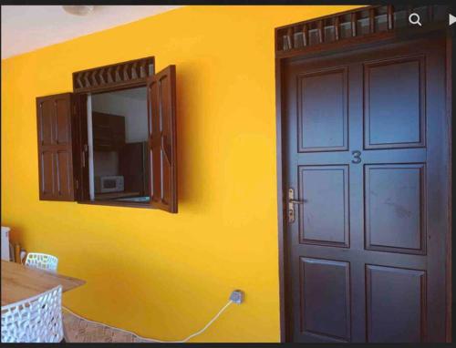 a yellow wall with a door and a mirror at Mana - SRFB 1 in Mana
