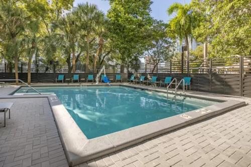 uma piscina com cadeiras azuis e árvores em Comfort Inn & Suites Downtown Brickell-Port of Miami em Miami