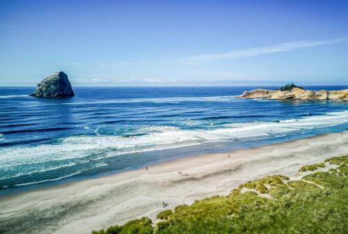 a beach with a large rock in the ocean at Pacific City Sand Dollar - Meredith Lodging in Pacific City