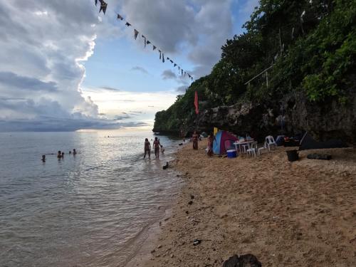 a group of people standing in the water on a beach at Gratum Beach Resort in Dapitan