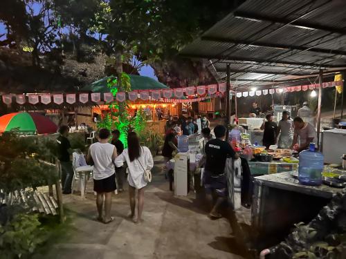 a group of people walking around a food stand at night at Gratum Beach Resort in Dapitan