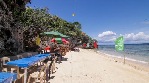 a row of tables and chairs on the beach at Gratum Beach Resort in Dapitan