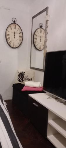 a room with two clocks on the wall and a couch at La familia in Ezeiza