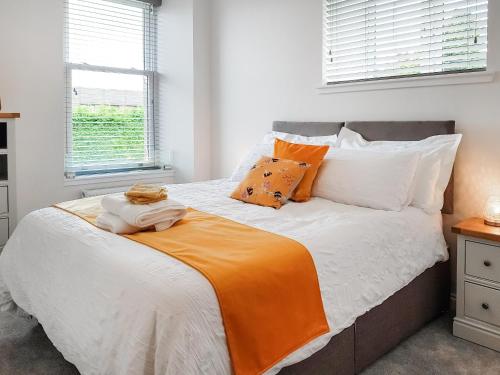 a bedroom with a bed with an orange blanket on it at Invergyle - Uk40566 in Falkland