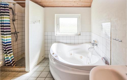 EgernsundにあるAmazing Home In Egernsund With 4 Bedrooms, Sauna And Wifiの窓付きのバスルーム(白いバスタブ付)