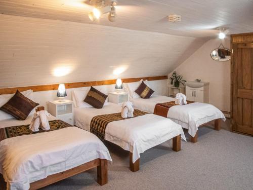 Cette chambre comprend 3 lits avec des draps blancs. dans l'établissement Hen Efail - Old Smithy, à Tregaron