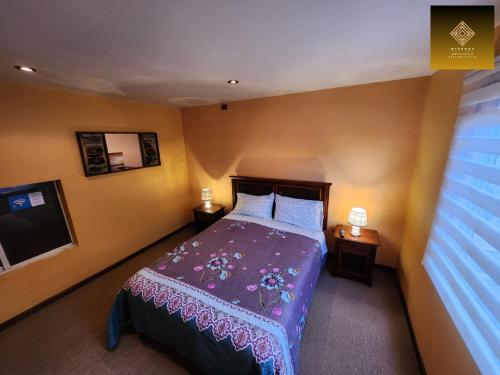 a bedroom with a bed with a purple blanket at Hostal Mirador Quellón in Quellón