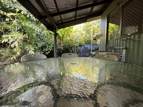 a glass table in a room with chairs and plants at Pete's Place in Berrimah