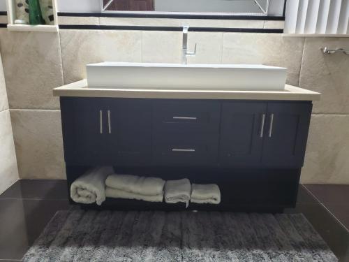 a bathroom vanity with a sink and towels under it at The Palms- Caribbean Estates -10 minutes from the beach- Gated Community in Portmore