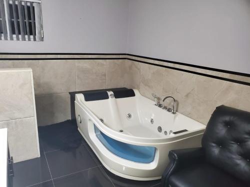 a bath tub in a room with a chair at The Palms- Caribbean Estates -10 minutes from the beach- Gated Community in Portmore