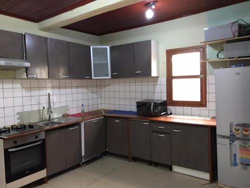 cocina con armarios grises, fregadero y nevera en Villa Sophie à Sassara Pk 12 Bangui, en Bangui