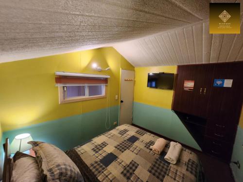 a bedroom with yellow and green walls and a bed at Hostal Mirador Quellón in Quellón