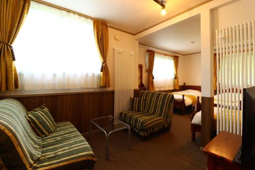 Habitación de hotel con cama, sofá y silla en Petit Resort Hotel Der Barte, en Zao Onsen