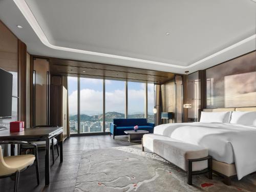 Diaoyutai Hotel Qingdao في تشينغداو: غرفة نوم بسرير كبير وكرسي ازرق