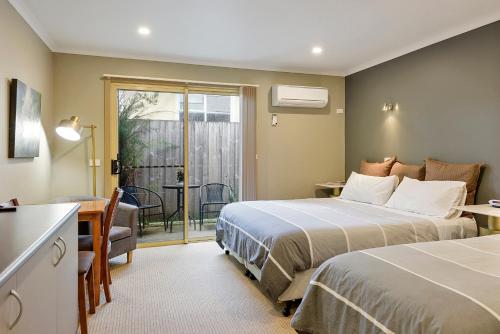 um quarto de hotel com duas camas e uma varanda em Motel Strahan em Strahan