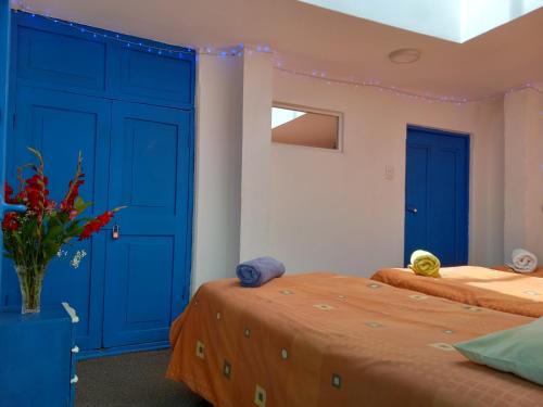2 camas en una habitación con puertas azules en Posada Azul Cusco, en Cusco