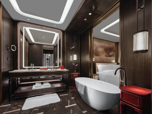 a bathroom with a tub and a bed and a sink at Diaoyutai Hotel Qingdao in Qingdao