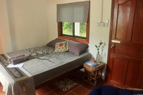 a small bedroom with a bed and a window at Beach House Cambodia in Koh Rong Sanloem