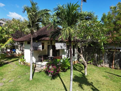 a house with palm trees in front of it at Di Abian Resort in Amed