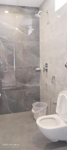 a white bathroom with a toilet and a shower at Seasons Stay in Vijayawāda