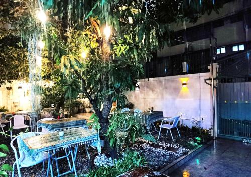 a patio with tables and chairs and a tree at Skylark bangkok 云雀 in Bangkok