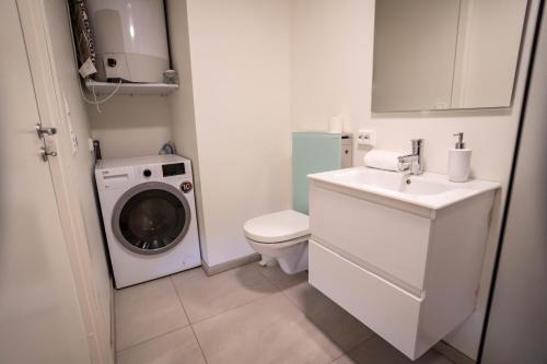 a bathroom with a washing machine and a washer at Vibrant apartment on bustling street, above a restaurant Perfect for tourists, in Stavanger