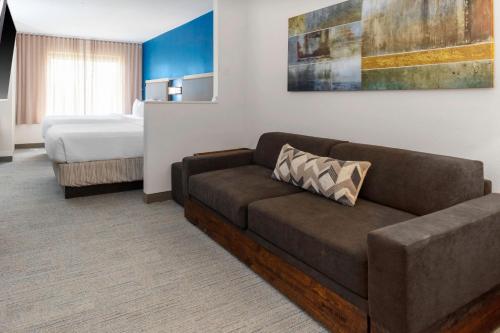 SpringHill Suites by Marriott Baton Rouge South في باتون روج: غرفة معيشة مع أريكة وسرير