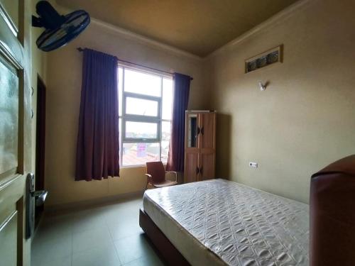 パレンバンにあるRian Kost - Hotel Penginapan Murah Pusat Kota Palembangのベッドと窓のある寝室