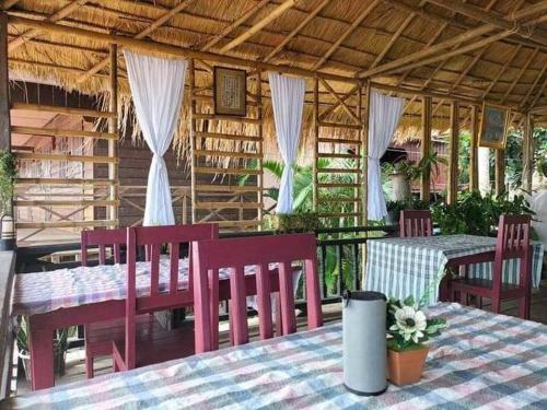 Muang KhôngにあるChampa Guesthouseの赤い椅子とテーブル、屋根のあるレストラン