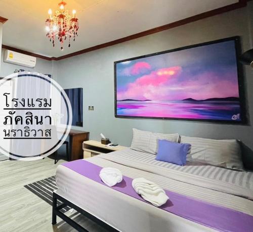 een slaapkamer met een bed met een groot schilderij aan de muur bij Paksina Hotel in Narathiwat