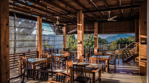 a restaurant with tables and chairs and large windows at La Seran Eco Resort in Bandarawela