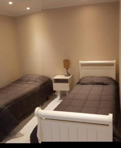 1 Schlafzimmer mit 2 Betten, einem Tisch und einem Spiegel in der Unterkunft Moderno Duplex - Alquiler en Comodoro Rivadavia in Comodoro Rivadavia