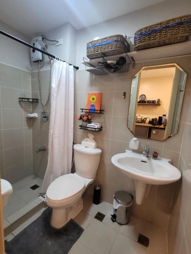 uma casa de banho com um WC, um lavatório e um espelho. em CasaBeNi staycation em Manila