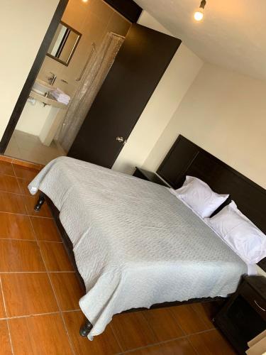 um quarto com uma cama grande com lençóis brancos e almofadas em Finca del Rincón em Guadalupe