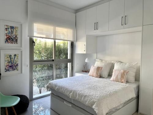 - une chambre blanche avec un lit et une fenêtre dans l'établissement Apartamentos Gran Sol con jardin, à Ciudad Quesada