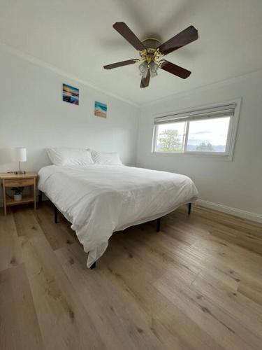 a white bedroom with a bed and a ceiling fan at Modern 3 King Beds, Beautiful Large Backyard, WFH, Long Stays, Waterfall, WI-FI, FWY, 25 mins to Beach in Thousand Oaks
