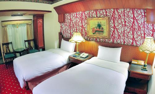 two beds in a hotel room with two lamps at KaRo Hotel in Kaohsiung