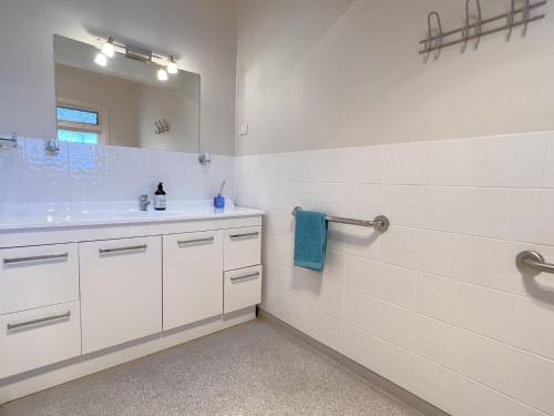 a white bathroom with a sink and a mirror at Inverloch Sands in Inverloch