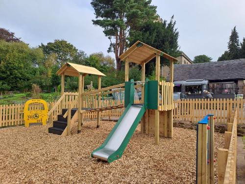 a wooden playground with a slide and a play structure at The White Hart Apartment Church View in Alton