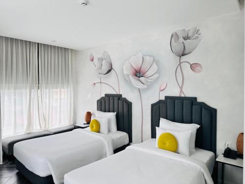 two beds in a room with flowers on the wall at Len's Hotel in Da Lat