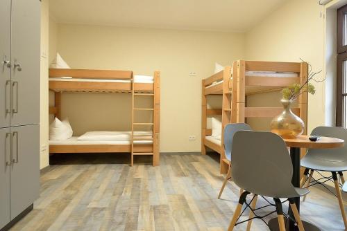 a room with a table and chairs and bunk beds at Hostel & Pension Alte Brauerei in Eisenach