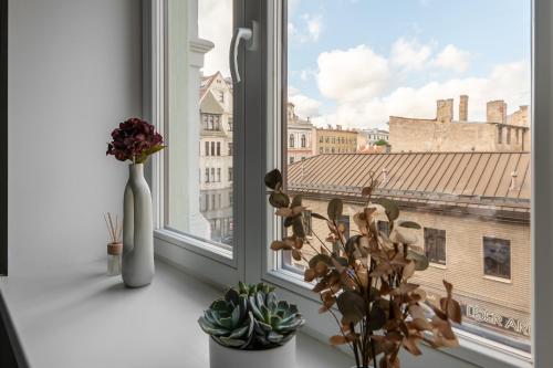 a window with a vase and flowers on a window sill at Historical House Apartments in Rīga