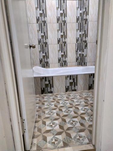 a bathroom with a shower with a tiled floor at Ador 46 Homestay Syariah & Kost in Mergan