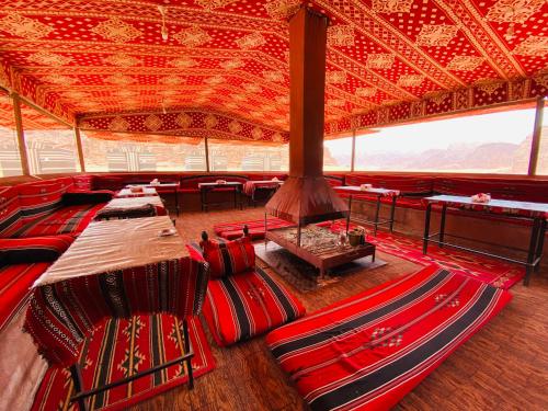 Habitación con sillas rojas y techo grande. en Bedouin Memories Camp, en Wadi Rum